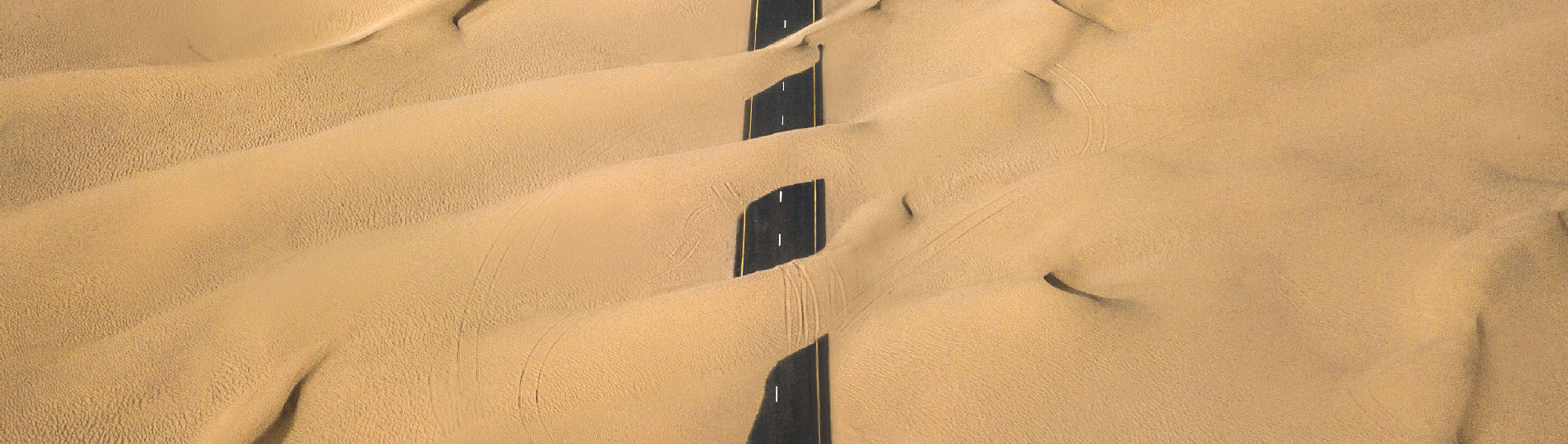 Photo montrant une route presque totalement recouverte par le sable